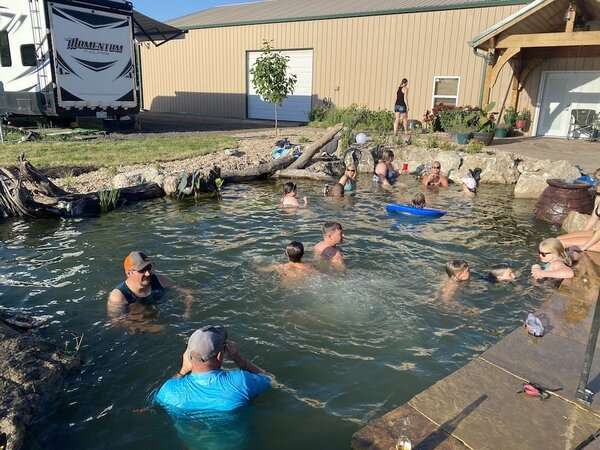Family and friends hanging out in a natural swimming pond