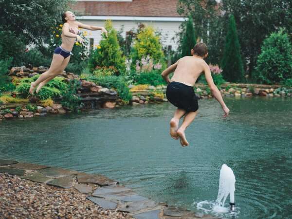 Kids jumping into a natural swim pond