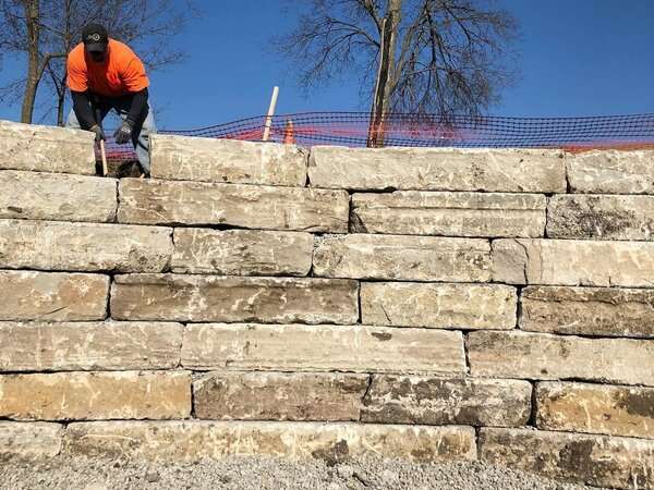Gradex employee leveling a stone retaining wall